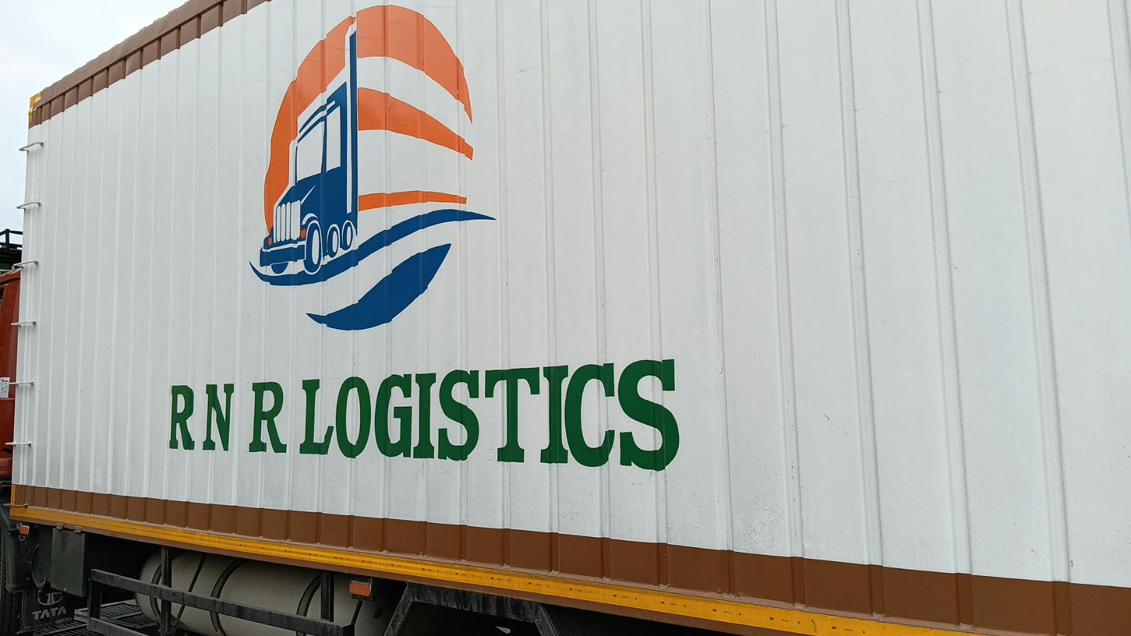 Actual RNR Logistics refrigerated truck photographed from the side with the branded container body visible.